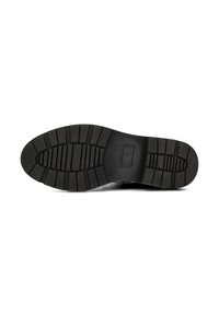 Suola di scarpa in gomma nera con un motivo testurizzato e scanalato per una maggiore aderenza. Presenta un design piatto e un'area del tallone rinforzata per una maggiore durata.
