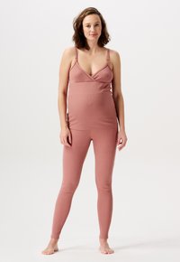 Graviditetsaktivklädesset i mjukt, töjbart, dämpat rosafärgat tyg; inkluderar en åtsittande topp med justerbara axelremmar och matchande leggings.