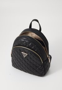 Schwarzer, gesteppter Leder-Rucksack mit goldfarbenen Beschlägen, der über zwei mit Reißverschluss versehene Fächer und einen oberen Tragegriff verfügt. Das Markenlogo ist gut sichtbar angebracht.