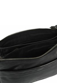 Borsa di pelle nera con chiusura con zip, dotata di un compartimento interno e foderata in tessuto. L'esterno ha una decorazione minimale e una texture liscia.