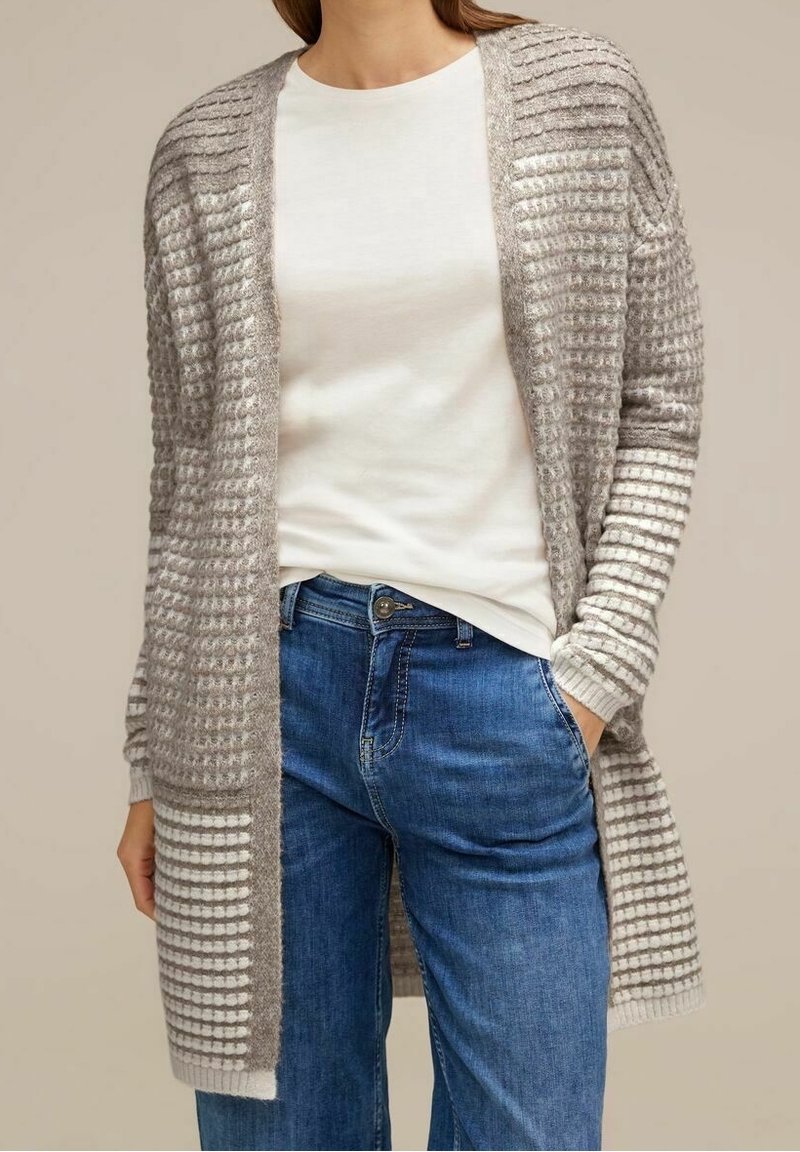 Světle šedý pletený cardigan s texturovanými a pruhovanými vzory, otevřený vpředu, s dlouhými rukávy a volným střihem, kombinovaný s bílou košili a modrými džíny.