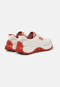 Sneakers con tomaia in tessuto bianco, suola in gomma rossa e dettagli texturizzati. Presentano un collo imbottito e chiusura con lacci.
