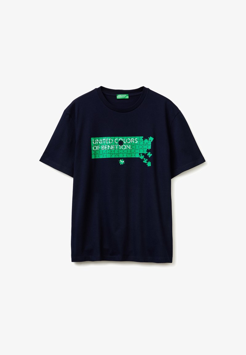 T-shirt bleu marine à manches courtes avec un graphisme puzzle vert formant l'inscription "United Colors of Benetton", des pièces du puzzle manquent sur le côté droit.