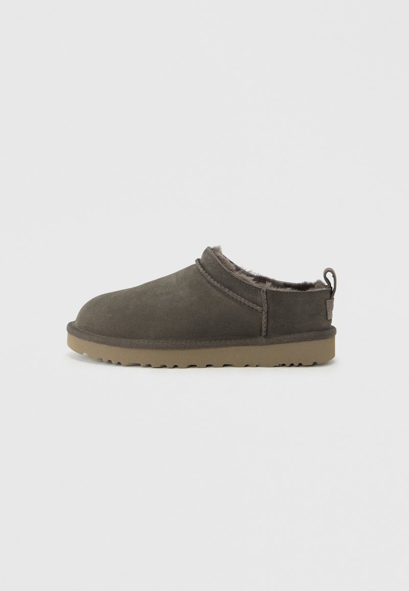 Chausson gris foncé à enfiler avec doublure intérieure douillette et semelle en caoutchouc beige, conçu pour le confort et la chaleur à l'intérieur.