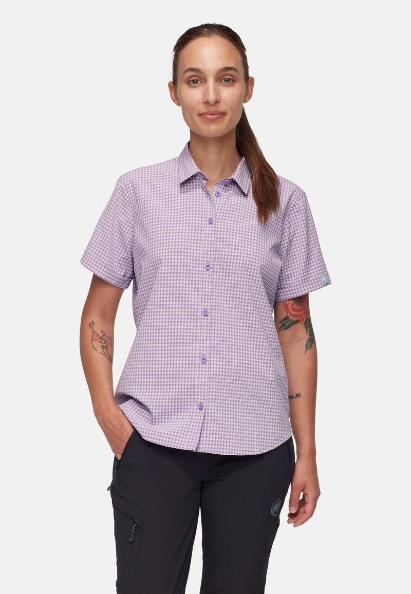 Camisa de cuadros vichy morada de manga corta, con botones en el frente y cuello clásico. Se lleva con pantalones oscuros, mostrando un tatuaje en el brazo.