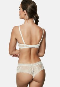 Lace lingerieset in off-white, bestaande uit een bralette met verstelbare bandjes en een bijpassende slip met golvende randen en bloemenpatronen.