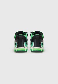 Zwarte en groene sneakers met een gestructureerde bovenkant, contrasterende witte accenten en een low-profile ontwerp. Voorzien van een trekband op de hiel.