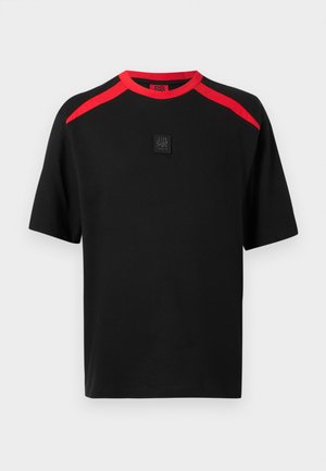 Maglietta nera a maniche corte con strisce rosse sulle spalle e colletto, con un piccolo logo a toppa nera al centro del petto.