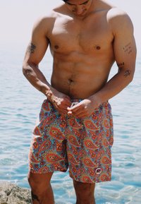 Färgglada badshorts med paisleymönster i nyanser av röd, blå och gul, med resår och dragsko i midjan samt logotags på sidan.