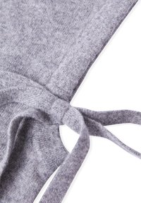 Tissu en maille grise avec une texture lisse, présentant un détail noué. L'image montre le bord et une section avec le nœud.