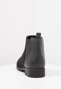 Botines negros de cuero texturizado y ante suave, con lengüeta para tirar y suela baja de goma.