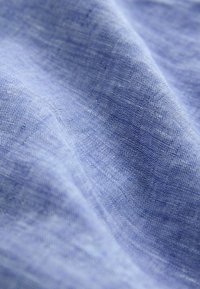 Tissu en lin bleu clair avec une surface douce et texturée, présentant des variations subtiles de teinte et une apparence légère et fluide.