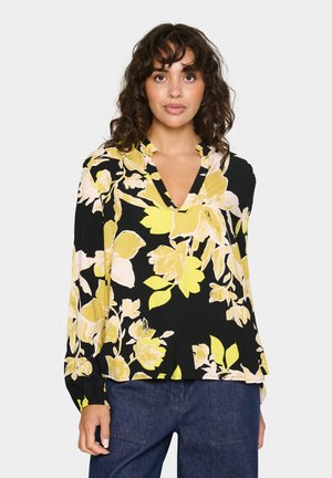 Blommig blus i svart med gula och rosa blommor. Har en v-ringning och långa ärmar med en avslappnad passform. Tillverkad av lättviktsmaterial.