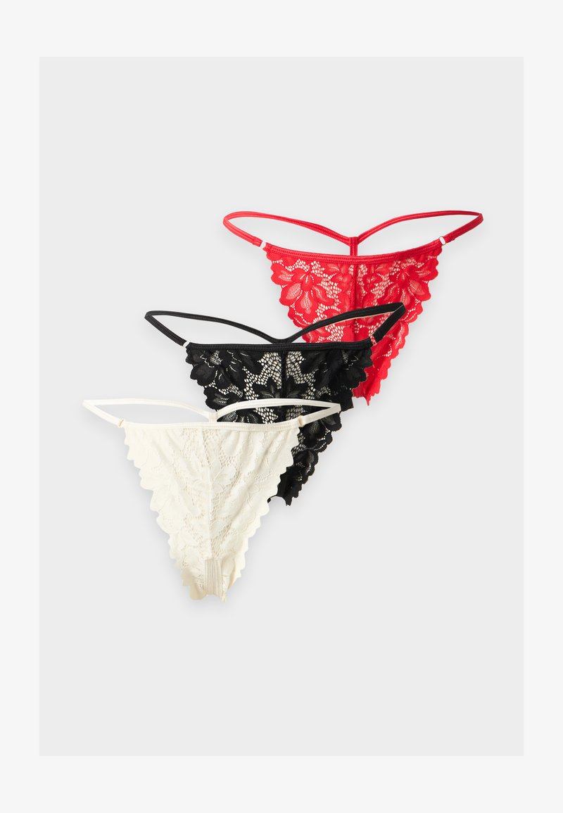 Trois strings en dentelle rouge, noir et blanc, disposés en rangée sur un fond clair.