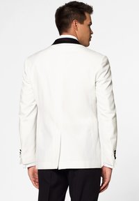 White tuxedo jacket with black satin shawl collar, single vent at the back, and black button accents on sleeves. Tailored fit design.