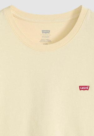 Jasnożółta bawełniana koszulka z okrągłym dekoltem i małą czerwoną naszywką z logo Levi's po lewej stronie.
