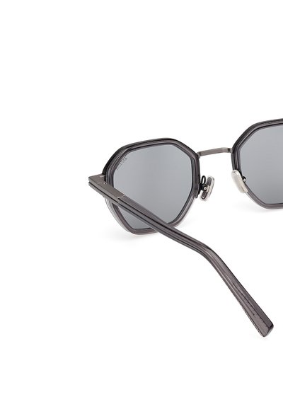 Ochelari de soare hexagonali negri cu lentile întunecate, accente metalice și tempori subțiri, având o finisare texturată pe ramă.