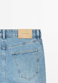 Jeans in denim azzurro chiaro vista posteriore con una singola tasca e una patch in pelle beige con la scritta "Massimo Dutti" sulla cintura.