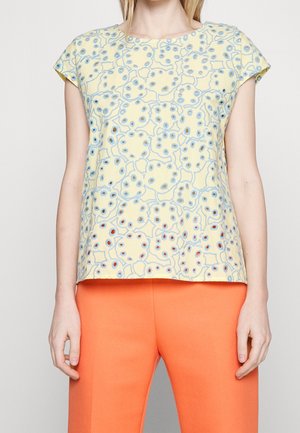 Kort mouw top in geel met een gestructureerd blauw patroon met cirkelvormige motieven, gecombineerd met oranje aansluitende broek. Soepele stof, losse pasvorm.