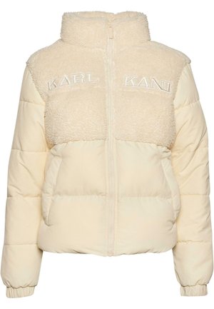 Crème pufferjack met een pluizige schapenvacht bovenkant en een gladde onderkant. Voorzien van een hoge kraag en geborduurde "KARL KANI" op de voorkant.