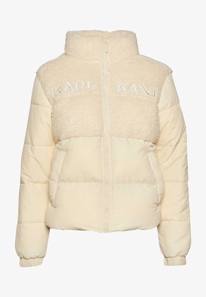 Kreemjas pufjakks, millel on pehme sherli ülaosa ja sile alumine osa. Omab kõrget krae ja volditud "KARL KANI" logot ees.