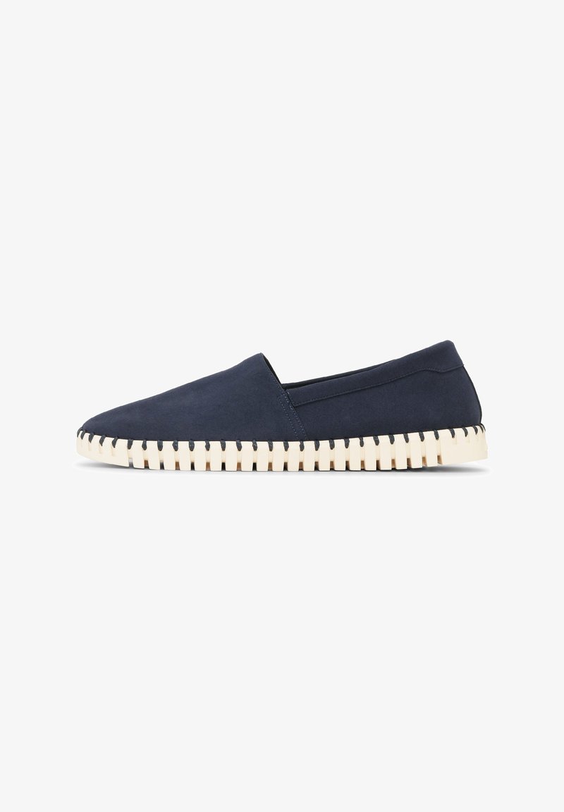 Chaussure navy blue slip-on avec empeigne lisse et semelle blanche épaisse dotée de profondes rainures horizontales pour l'adhérence.