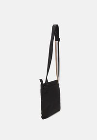 Black fabric shoulder bag with a smooth texture, adjustable strap, and a top opening. Features contrasting accent colors on the strap.