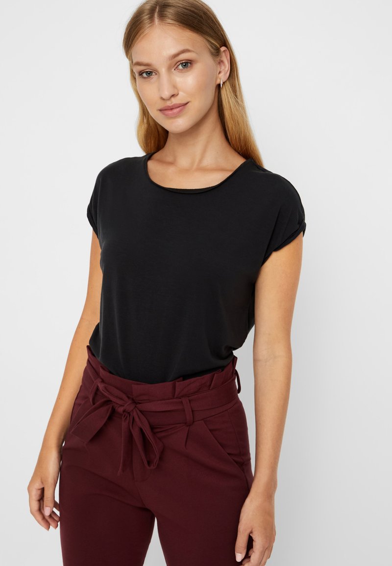 Top negro de manga corta con cuello redondo, combinado con pantalones burdeos de cintura alta con lazo en la cintura y textura suave.