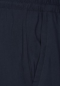Navyblauwe stof met een gladde textuur, voorzien van een elastische tailleband en zijzakken, met getailleerde plooi-details.