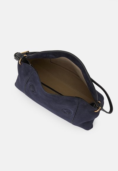 Bolsa de camurça com uma cor azul marinho profundo. Apresenta uma alça de couro e compartimentos interiores, contornados com costura subtil e ferragens em tom dourado.
