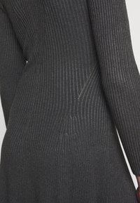 Abito a costine in carbone con maniche lunghe, caratterizzato da una trama sottile e da un dettaglio con zip nascosta sul lato per una funzionalità aggiuntiva.