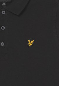 Czarny polo dla dzieci w wieku 9-10 lat z trzema guzikami i małym haftowanym logiem orła w kolorze żółtym na piersi.