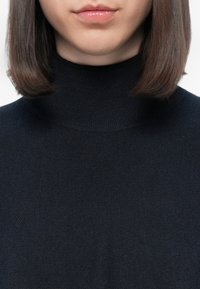 Maglione a collo alto di un elegante blu notte con un design aderente. Realizzato in un morbido tessuto strutturato con una leggera rigatura sul colletto e sull'orlo.