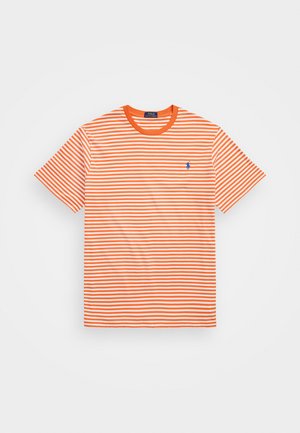 T-shirt rayé orange et blanc avec un col rond et des manches courtes. Présente un petit logo bleu sur la poitrine gauche. Matière en mélange de coton.