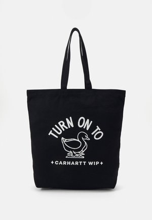 Sac fourre-tout noir avec de longues anses, comportant un texte blanc "TURN ON TO" au-dessus d'une illustration de canard et "CARHARTT WIP" en dessous.