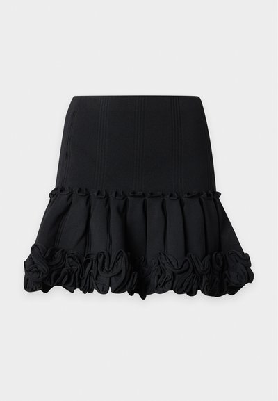 Mini-jupe noire avec une partie supérieure ajustée et un ourlet à volants le long du bord inférieur.