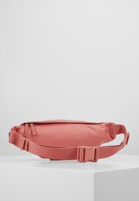 Väskor i mjuk korallfärgad tyg, med ett huvudfack med dragkedja, hållbar justerbar rem och plastspänne. Slät textur.