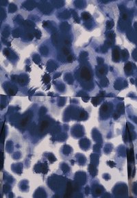 Námořnická modř a bílá látka s abstraktním vzorem, který zahrnuje rozmazané skvrny a fleky. Hladká textura, jemný pád a nepravidelné tvary.