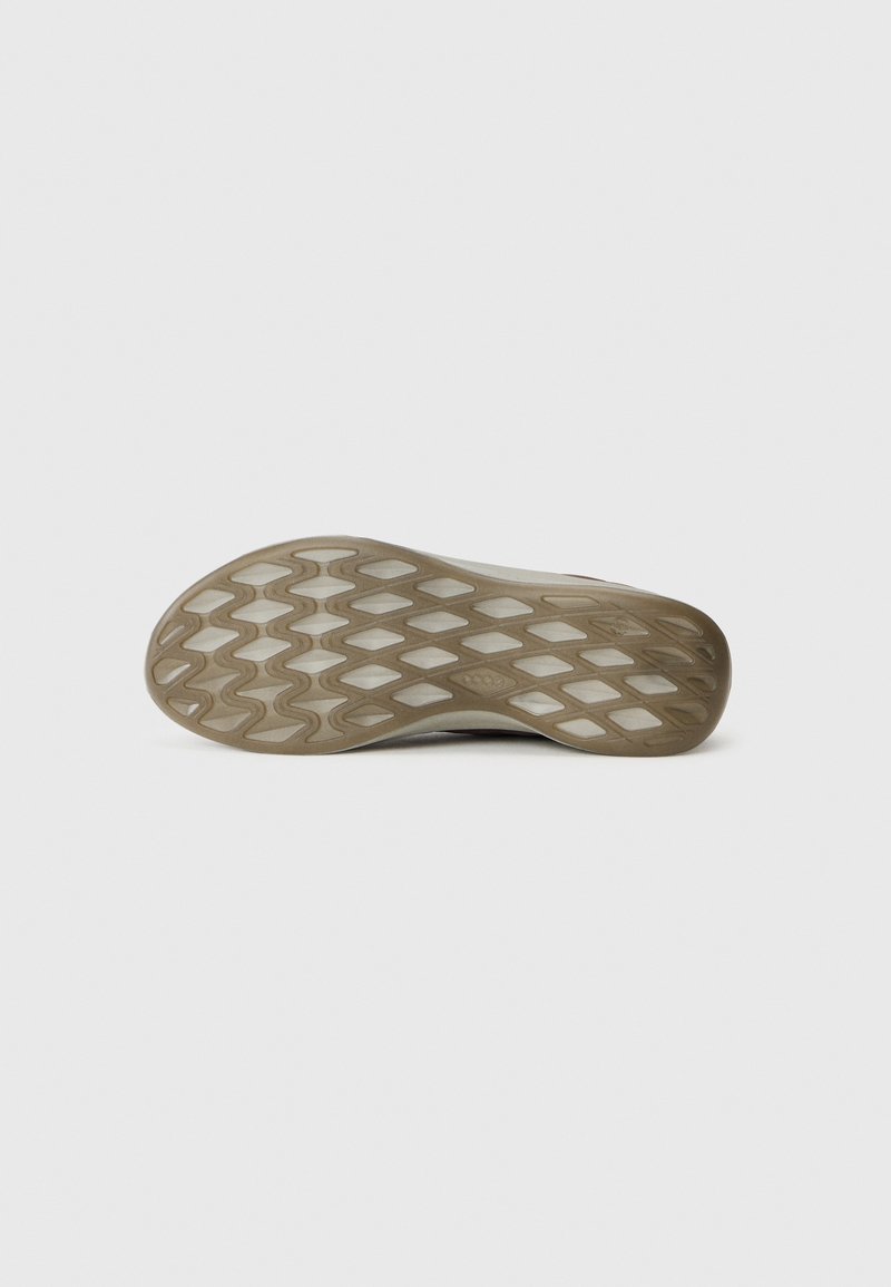 Sole od beżowego sneaker'a z diamentowym i falistym wzorem bieżnika na jednolitym białym tle.