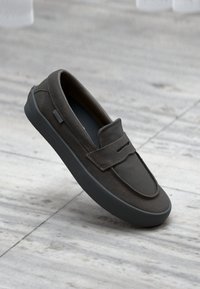 Mørkebrune semskede slip-on-sko med rund tå, flad gummisål og minimalistisk design. Har en sømdetalje og diskrete udskæringer.