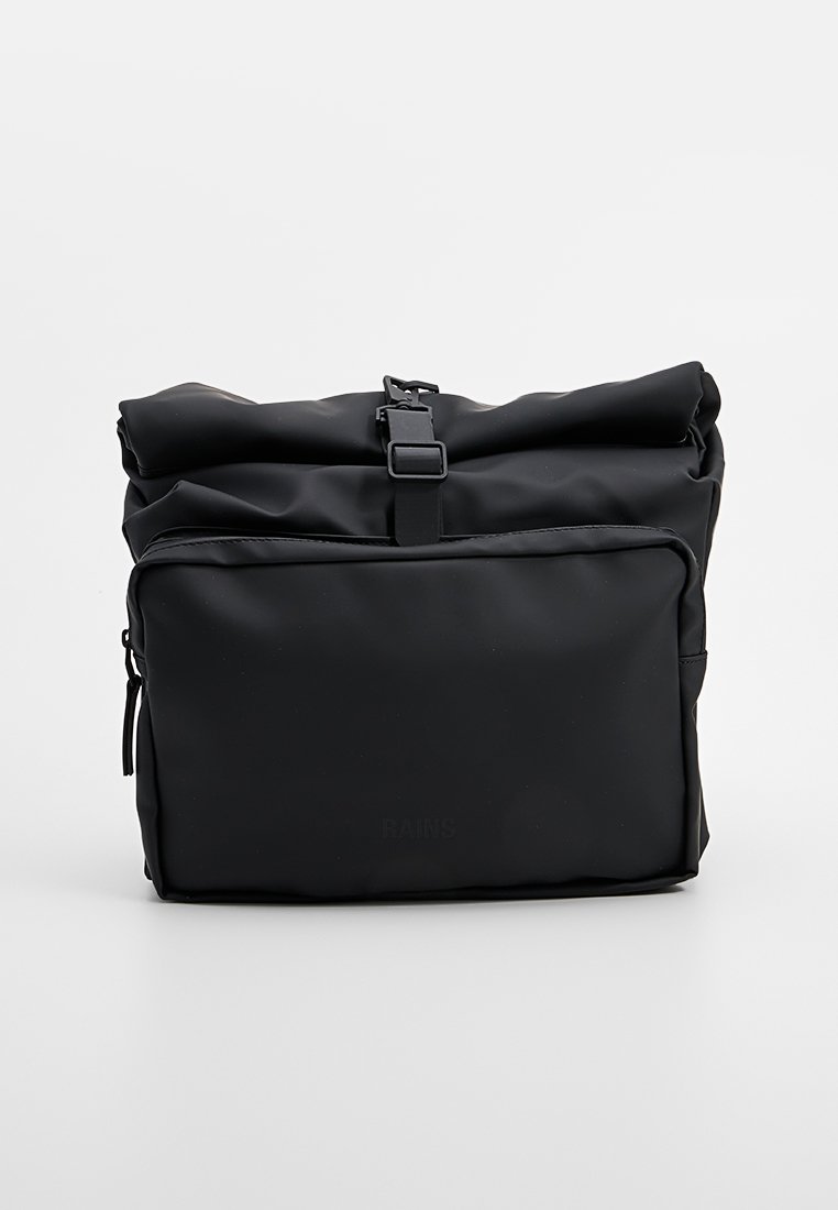 Sac à dos noir à rabat fabriqué en matériau imperméable, comportant une poche zippée à l'avant et un design minimaliste avec une fermeture à boucle robuste.