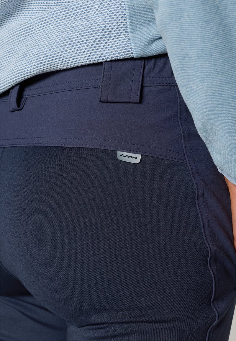 Granatowe, elastyczne spodnie sportowe o gładkiej teksturze i dopasowanym kroju. Posiadają małą metkę z logo marki "ICEPARK."