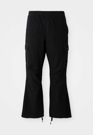 Zwarte cargobroek met een elastische tailleband, uitgerust met zijzakken en flared pijpen met ritssluitingen bij de manchetten, weergegeven tegen een witte achtergrond.