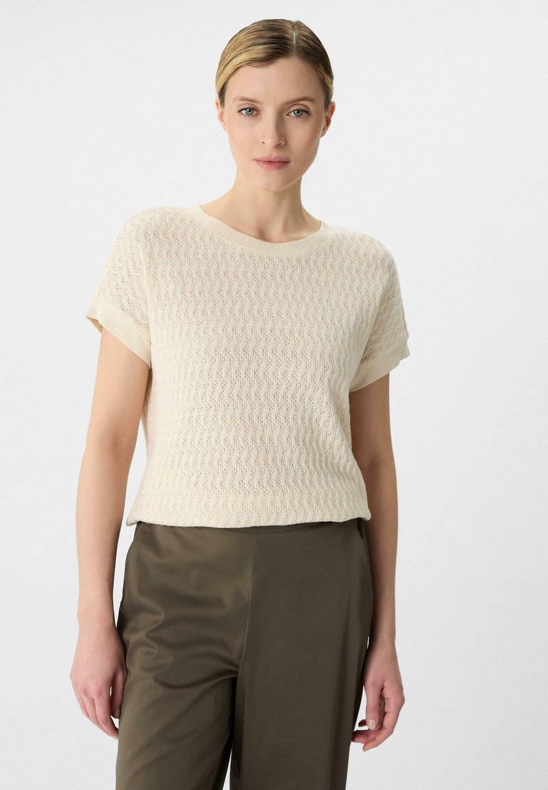 Lichtromige gebreide top met korte mouwen, met een gestructureerd patroon, ronde halslijn, contrasterende ribgebreide manchetten en een relaxed fit.