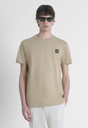 Beige katoenen T-shirt met korte mouwen, ronde halslijn en een klein zwart logo-opdruk op de borst. Soepele textuur, regular fit.