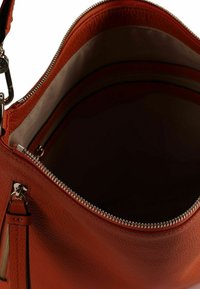 Oranje leren handtas met ritssluiting. De binnenkant is voorzien van een beige voering en een ritssluitingvak. Gladde textuur en afgeronde vorm.