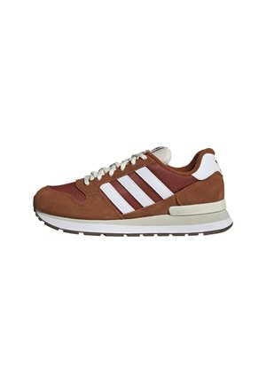 Braun-weißer Adidas-Sneaker mit weißen Schnürsenkeln, drei weißen Streifen an der Seite und einer Gummisohle mit strukturiertem Profil.