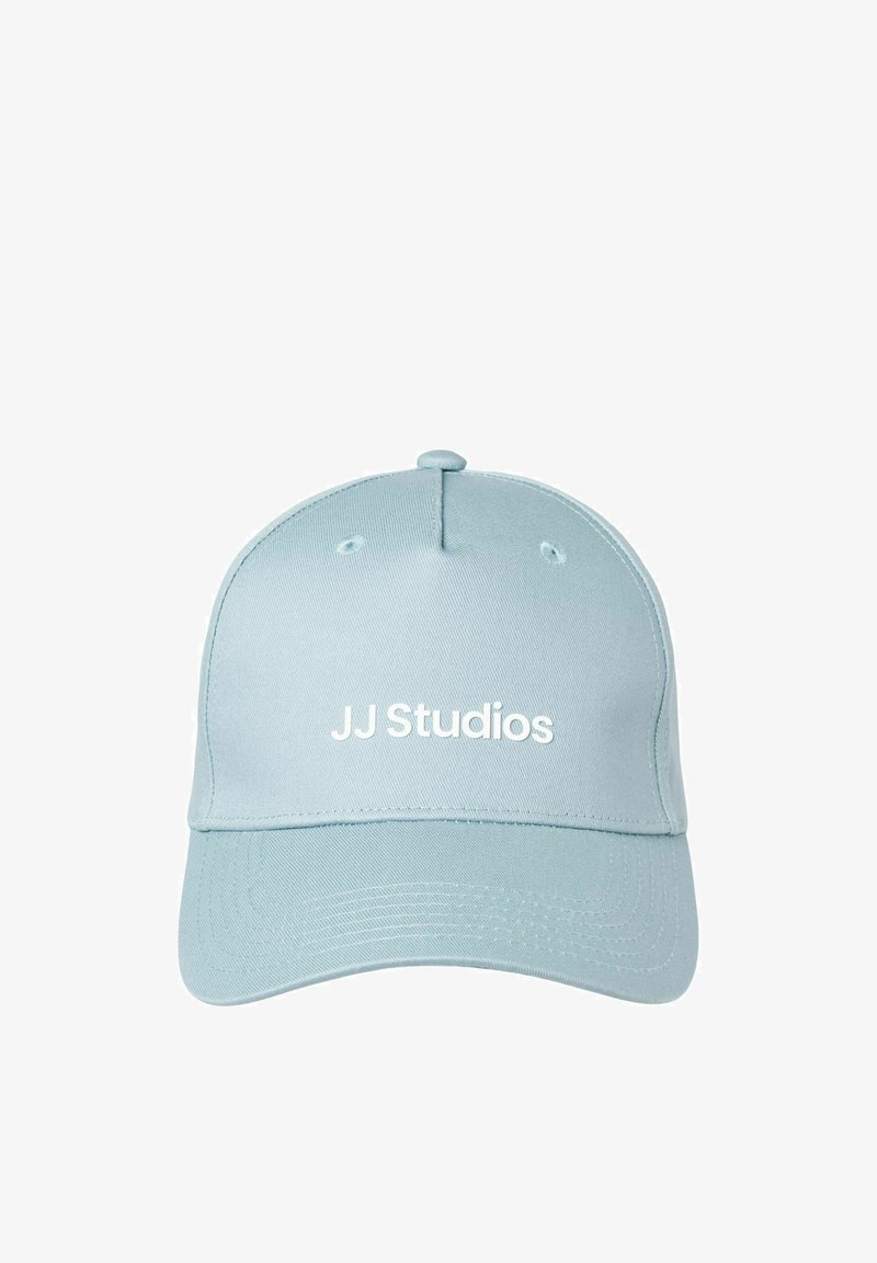 Gorra de béisbol azul claro con corona redondeada y visera rígida, con el texto "JJ Studios" en blanco bordado en la parte frontal.