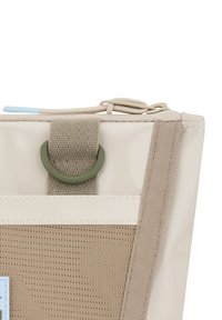 Sacchetto in tessuto beige con superficie testurizzata, un anello metallico verde e un tirante della zip azzurro chiaro. Il design presenta una finitura liscia e lucida.