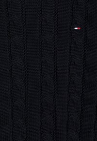Pullover a maglia blu navy con motivo a trecce, caratterizzato da una superficie testurizzata e un piccolo logo rosso, bianco e blu.